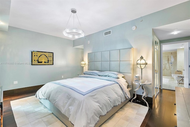 bedroom featuring baseboards, visible vents, wood finished floors, and an inviting chandelier