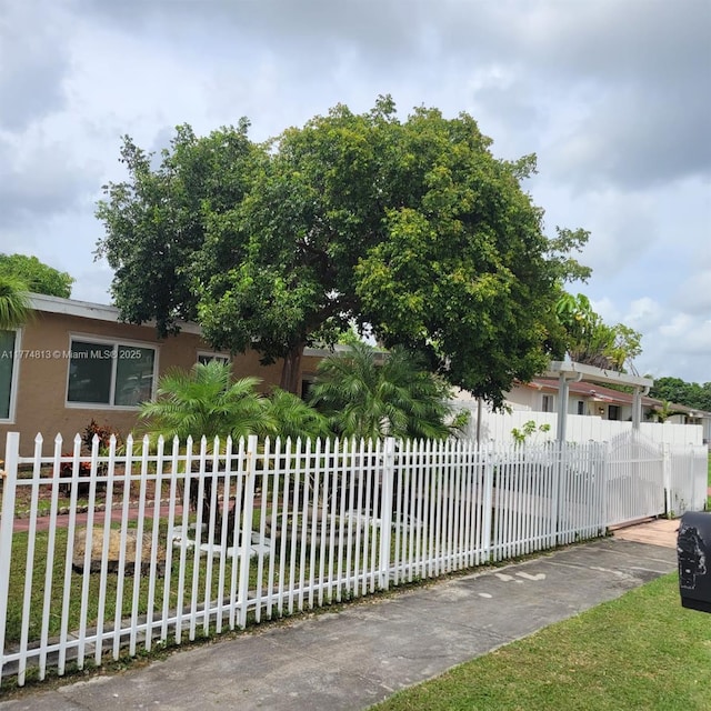 view of property hidden behind natural elements with a fenced front yard and stucco siding