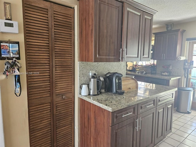 kitchen with decorative backsplash, a textured ceiling, light tile patterned floors, and light stone counters