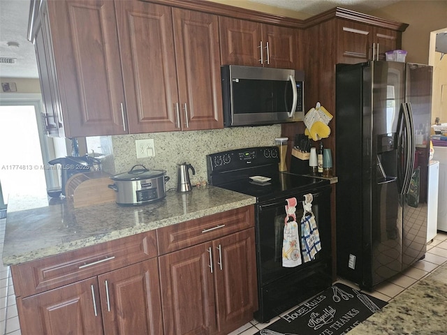 kitchen with stainless steel microwave, light stone countertops, light tile patterned floors, black electric range, and fridge with ice dispenser