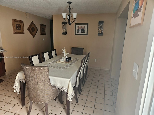 dining room with a notable chandelier, a textured ceiling, baseboards, and light tile patterned floors