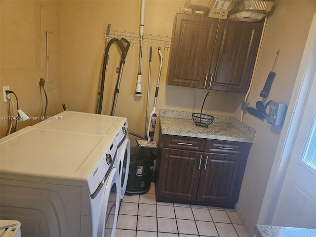 clothes washing area featuring light tile patterned floors, cabinet space, and washer and dryer