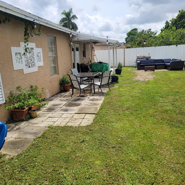 view of yard with fence, an outdoor living space, and a patio