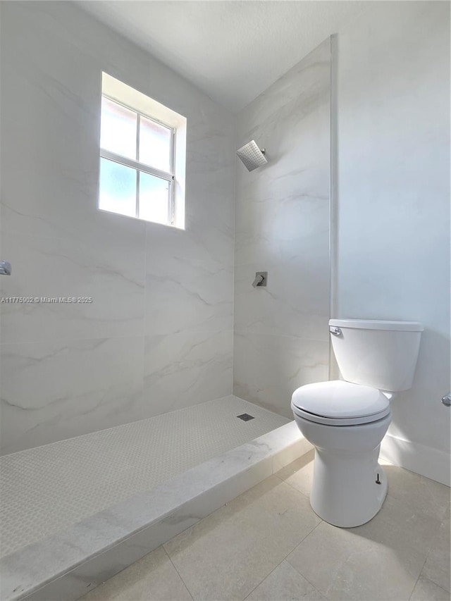 full bathroom with toilet, tiled shower, and tile patterned flooring