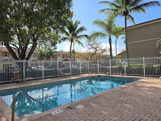 community pool with a residential view, a patio area, and fence