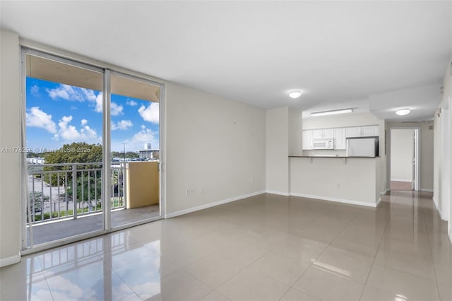 empty room featuring light tile patterned floors, baseboards, and expansive windows
