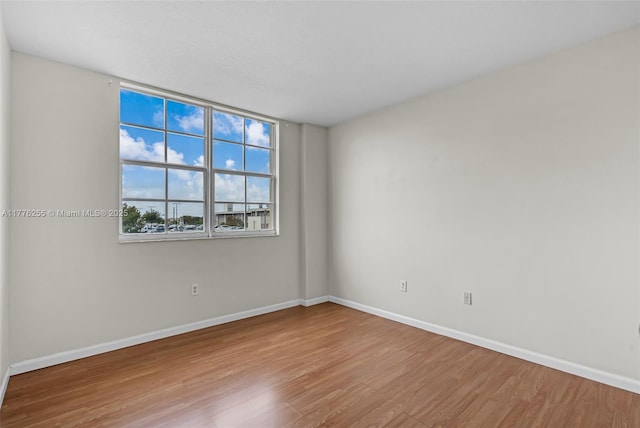 spare room featuring baseboards and wood finished floors