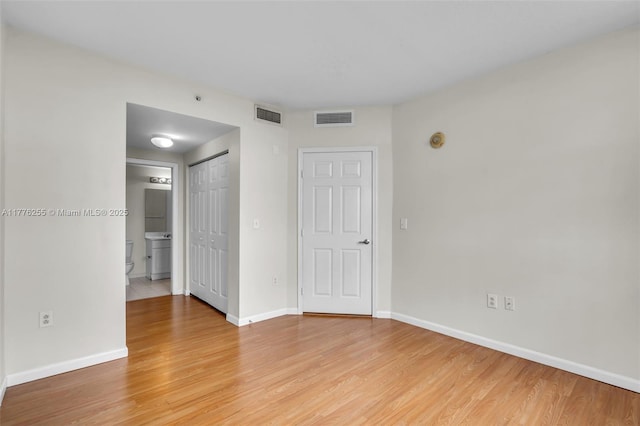 spare room featuring baseboards, visible vents, and light wood-type flooring