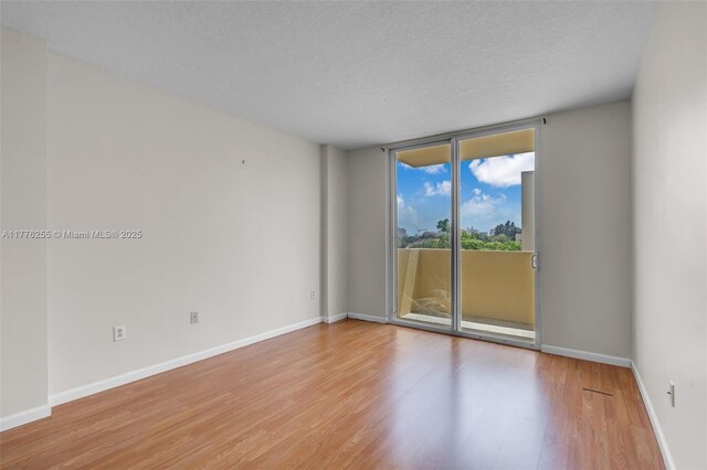 empty room featuring baseboards, expansive windows, and wood finished floors
