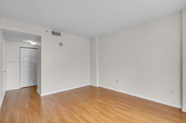 empty room with baseboards, visible vents, and light wood-type flooring