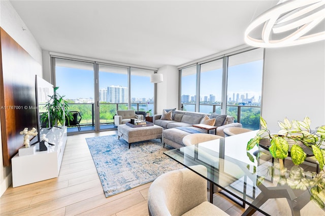 living room with a wall of windows, a view of city, wood finished floors, and a healthy amount of sunlight