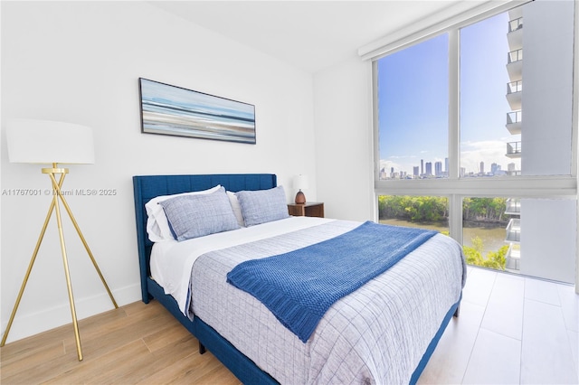 bedroom featuring baseboards, a city view, and wood finished floors
