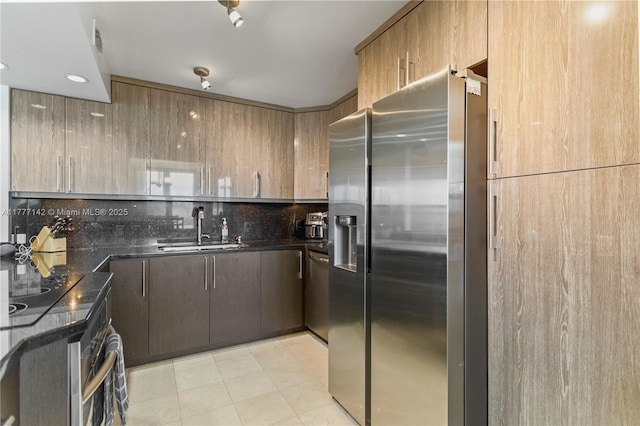 kitchen featuring dark stone countertops, tasteful backsplash, a sink, and stainless steel appliances