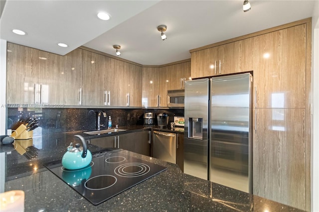 kitchen featuring tasteful backsplash, recessed lighting, dark stone countertops, appliances with stainless steel finishes, and a sink