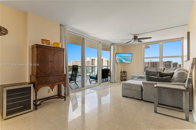 living room with wine cooler, a ceiling fan, and a wall of windows