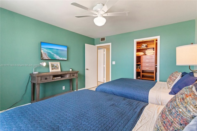 bedroom with a spacious closet, visible vents, and ceiling fan