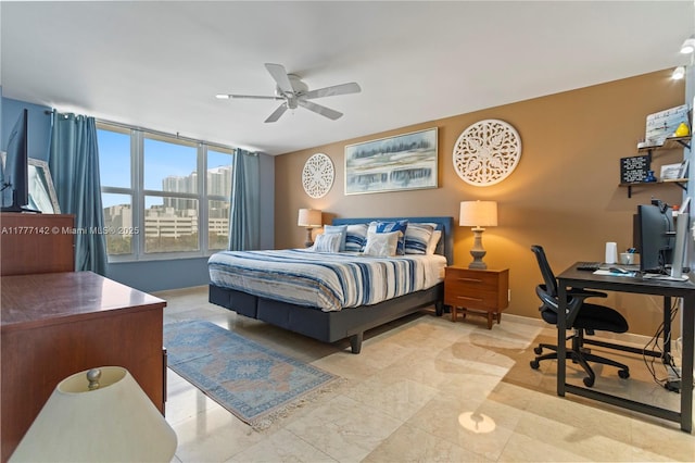 bedroom featuring baseboards, ceiling fan, and a city view