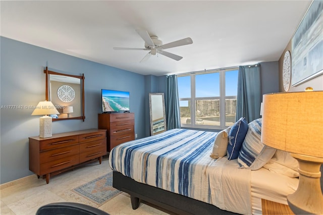bedroom featuring expansive windows, baseboards, and a ceiling fan