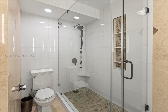 full bath featuring toilet, a stall shower, recessed lighting, and tile walls