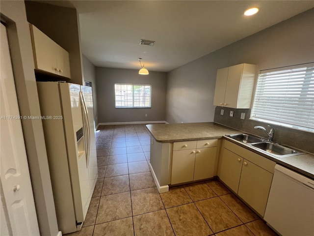kitchen with light tile patterned flooring, a sink, a peninsula, white appliances, and visible vents