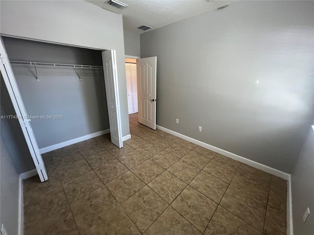 unfurnished bedroom featuring tile patterned floors, a closet, baseboards, and visible vents