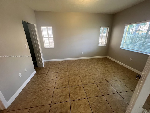 tiled spare room featuring baseboards