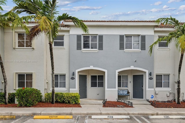 townhome / multi-family property featuring uncovered parking and stucco siding