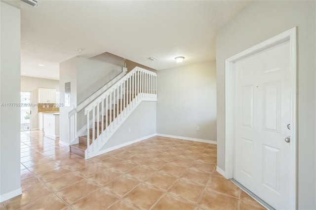 spare room featuring light tile patterned floors, baseboards, and stairway