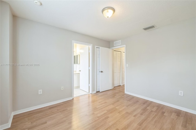 unfurnished bedroom featuring visible vents, light wood-type flooring, and baseboards