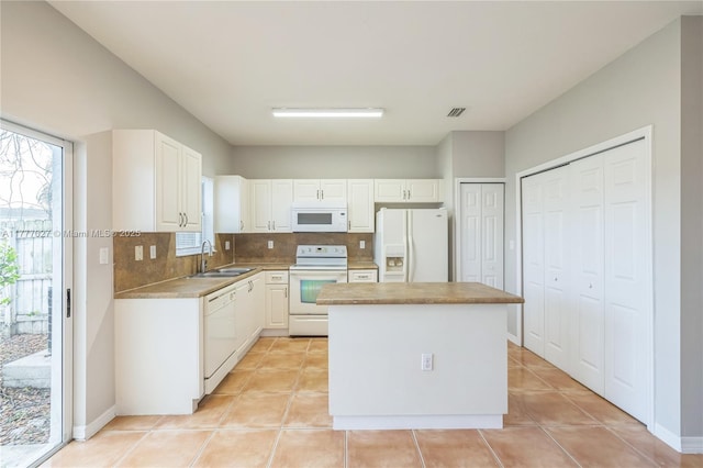 kitchen featuring tasteful backsplash, a sink, white appliances, white cabinetry, and a kitchen island