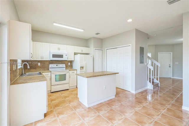 kitchen featuring white appliances, light countertops, backsplash, a kitchen island, and a sink