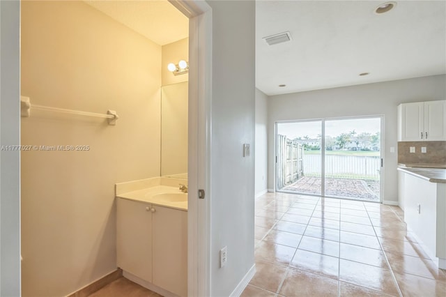 bathroom with tasteful backsplash, vanity, baseboards, tile patterned floors, and visible vents