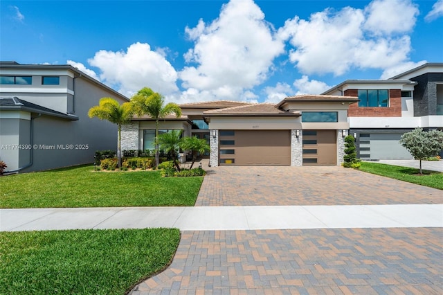 contemporary house with stucco siding, an attached garage, stone siding, decorative driveway, and a front lawn