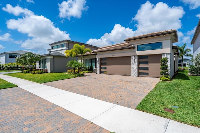 contemporary home with a front lawn, decorative driveway, an attached garage, and stucco siding