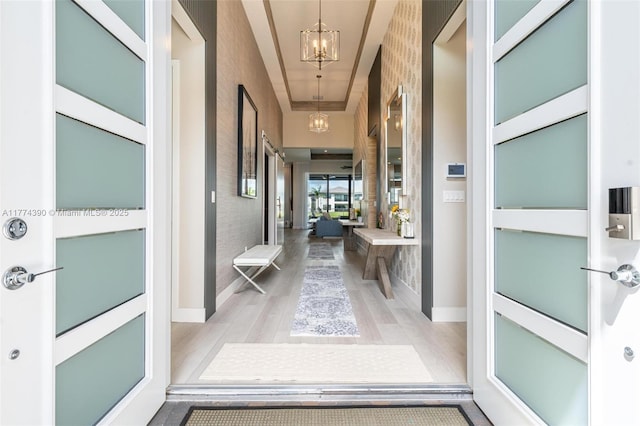 corridor featuring baseboards, a chandelier, and wood finished floors