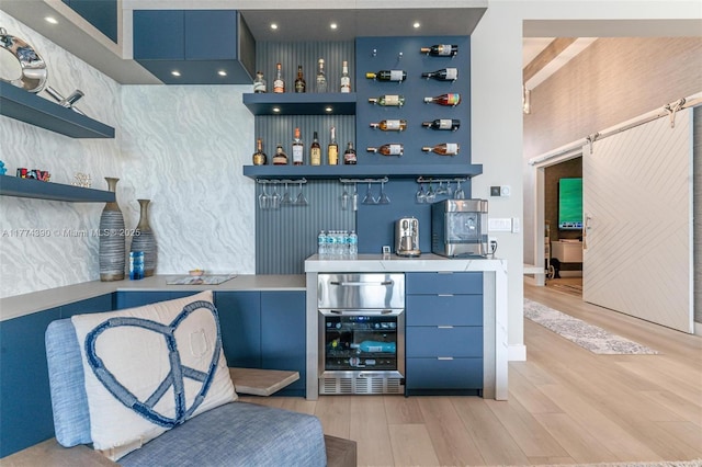 bar with a bar, light wood-style floors, and beverage cooler