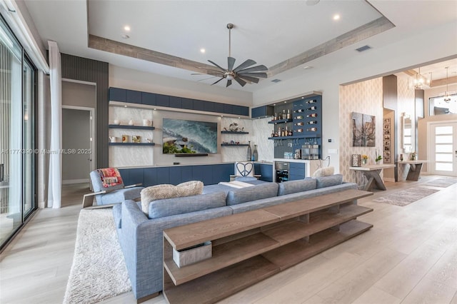 living area featuring a tray ceiling, wood finished floors, and bar area