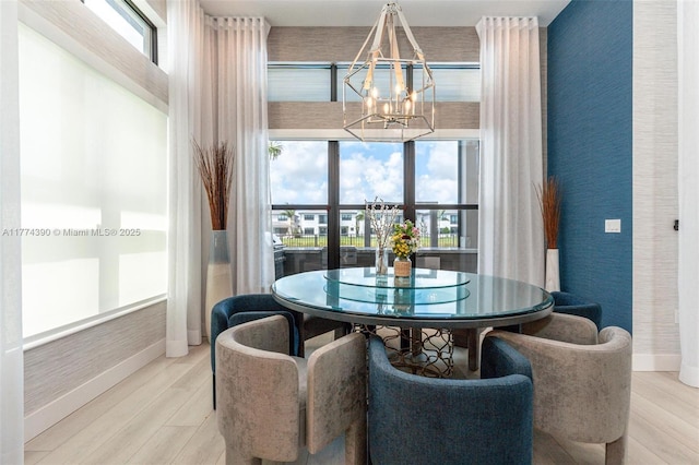 dining space with baseboards, wallpapered walls, wood finished floors, and a chandelier