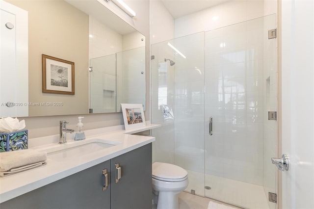 bathroom with toilet, vanity, and a shower stall
