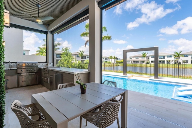 view of pool with fence, a grill, a water view, a ceiling fan, and area for grilling
