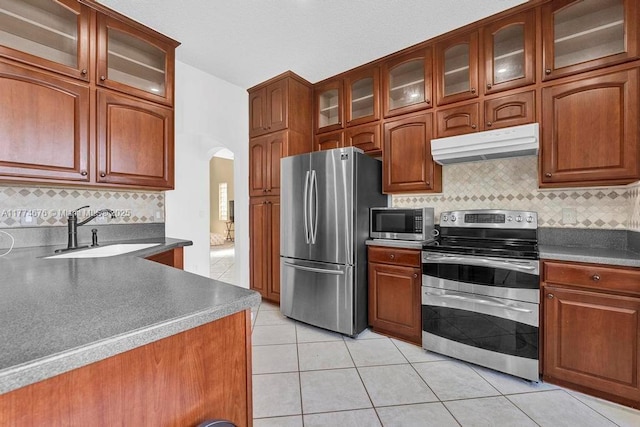 16226 Opal Creek Dr, Weston, FL 33331 - kitchen featuring a sink, arched walkways, under cabinet range hood, appliances with stainless steel finishes, and decorative backsplash