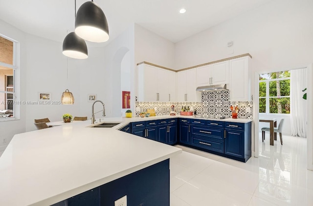 1604 Victoria Pointe Ln, Weston, FL 33327 - kitchen with blue cabinetry, under cabinet range hood, light tile patterned flooring, light countertops, and a towering ceiling
