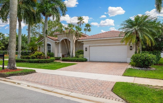 1604 Victoria Pointe Ln, Weston, FL 33327 - mediterranean / spanish-style house with stucco siding, decorative driveway, an attached garage, a tiled roof, and a front lawn