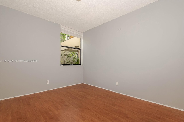 unfurnished room featuring baseboards, a textured ceiling, and wood finished floors