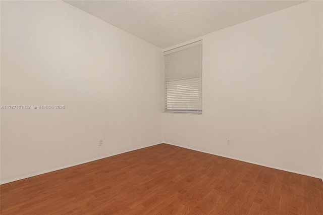 spare room with baseboards, lofted ceiling, and wood finished floors