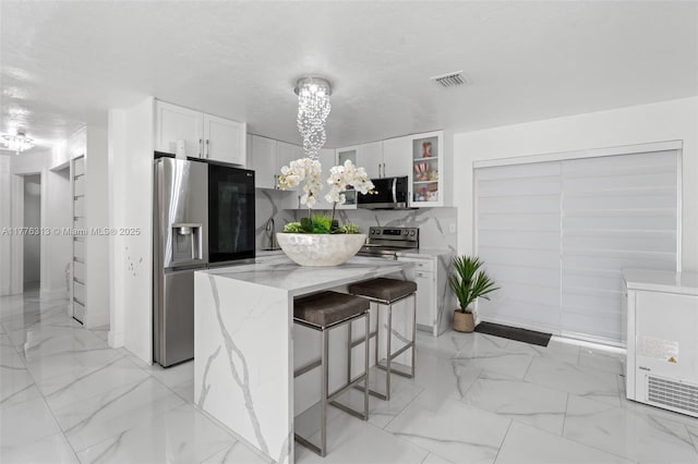 4814 SW 20th St, Fort Lauderdale, FL 33317 - kitchen featuring a kitchen breakfast bar, white cabinets, visible vents, appliances with stainless steel finishes, and marble finish floor
