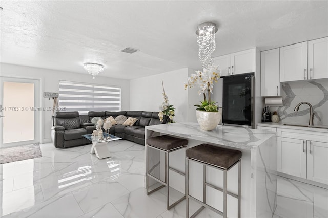 4814 SW 20th St, Fort Lauderdale, FL 33317 - kitchen featuring refrigerator, white cabinetry, light stone countertops, marble finish floor, and a sink