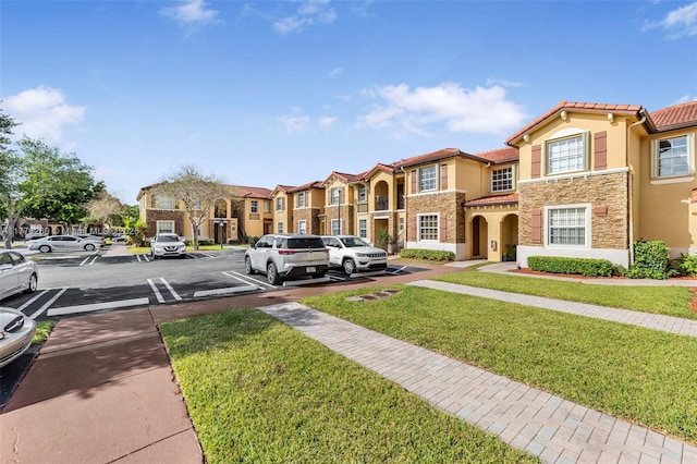 townhome / multi-family property featuring stucco siding, a front lawn, uncovered parking, a residential view, and a tiled roof