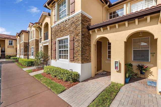 view of exterior entry with stucco siding, stone siding, and a residential view