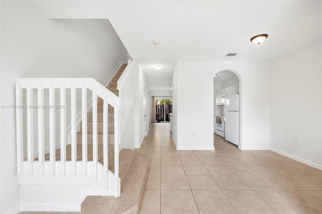 interior space with visible vents, baseboards, stairway, arched walkways, and light tile patterned floors